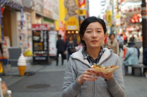 商店街でたこ焼きを食べる女性