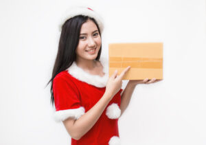 段ボール箱を持つサンタ姿の女性