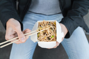 紙箱の弁当箱の昼食をとる男性の手元